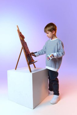 Stüdyoda sehpada soyut sanat eserleri çizen genç bir çocuk. Sanatsal eğitim kavramı, çocukluk yaratıcılığı, güzel sanatlar eğitimi, hayal gücü gelişimi ve yaratıcı ifade.