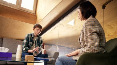 Gençler psikoloji terapisi sırasında su dökerler. Terapi alanında sakin destekleyici atmosfer, duygusal güvenlik, zihinsel sağlık danışmanlığı, bakım, empati ve stres rahatlama kavramı.