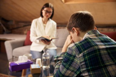 Profesyonel psikologla psikoterapi seansında olan genç bir çocuk. Ruh sağlığı hizmetleri, gençlik danışmanlığı, psikolojik bakım, terapi pazarlama ve sağlık hizmetleri iletişimi kavramı.