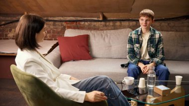 Genç bir çocuk ruh sağlığı danışma seansı sırasında psikologla konuşuyor. Duygusal destek kavramı, gençlik terapisi, profesyonel psikoloji hizmetleri ve zihinsel refah programları.