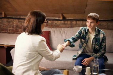 Başarılı terapi seansından sonra genç bir çocuk psikologla el sıkışıyor. Pozitif tedavi sonucu, ruhsal sağlık hizmetleri pazarlaması ve duygusal iyileşme desteği kavramı.