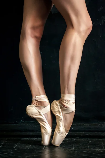 Close-up bailarinas pernas em pointes no chão de madeira preta — Fotografia de Stock