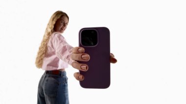 Beyaz arka planda kameraya doğru akıllı telefon tutan genç bir kadın. Mobil teknoloji tanıtımı, akıllı telefon reklamcılığı, alet pazarlama ve modern dijital iletişim cihazları kavramı.