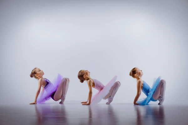 Three little ballet girls sitting in tutus and posing together — Stock Photo, Image