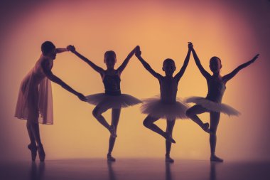 Three little ballerinas dancing with personal ballet teacher in dance studio clipart