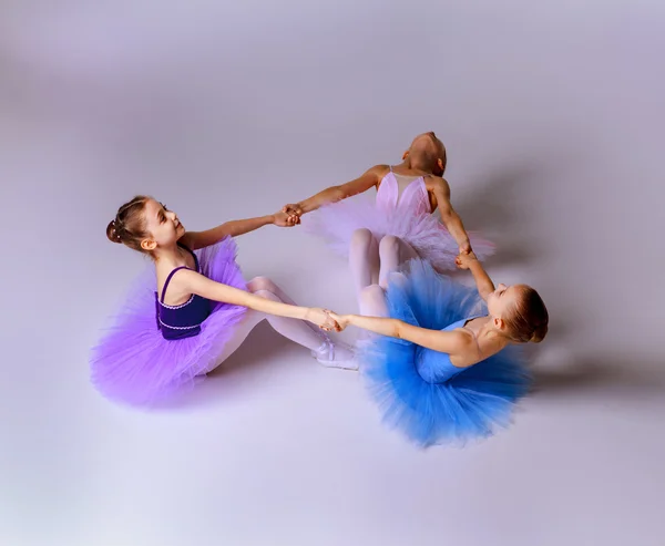 Tres pequeñas chicas de ballet sentadas en tutú y posando juntas —  Fotos de Stock
