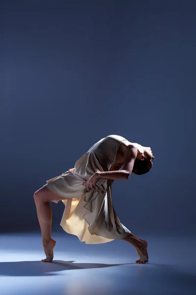 Junge schöne Tänzerin in beigem Kleid tanzt auf grauem Hintergrund — Stockfoto