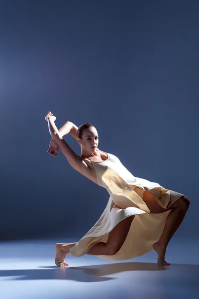 Joven hermosa bailarina en vestido beige bailando sobre fondo gris — Foto de Stock