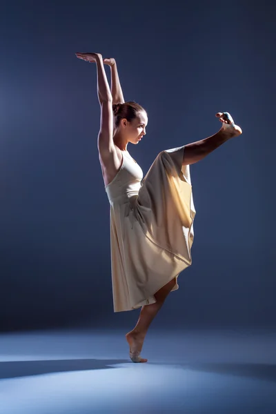 Giovane bella ballerina in abito beige che balla su sfondo grigio — Foto Stock
