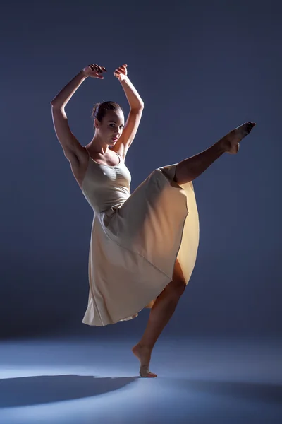 Joven hermosa bailarina en vestido beige bailando sobre fondo gris — Foto de Stock