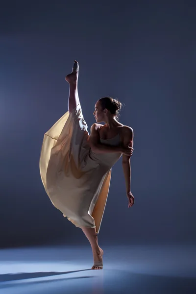 Joven hermosa bailarina en vestido beige bailando sobre fondo gris — Foto de Stock