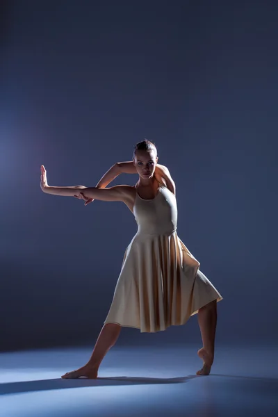 Joven hermosa bailarina en vestido beige bailando sobre fondo gris — Foto de Stock