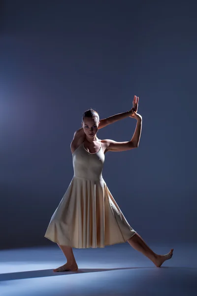 Joven hermosa bailarina en vestido beige bailando sobre fondo gris — Foto de Stock