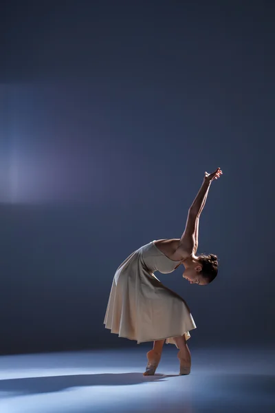 Joven hermosa bailarina en vestido beige bailando sobre fondo gris — Foto de Stock