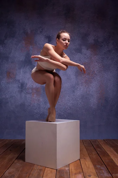 Junge schöne Tänzerin in beiger Badebekleidung posiert auf White Cube — Stockfoto