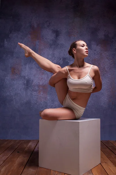 Young beautiful dancer in beige swimwear posing on white cube — 스톡 사진