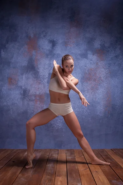 Junge schöne Tänzerin in beiger Badebekleidung tanzt auf fliederfarbenem Hintergrund — Stockfoto