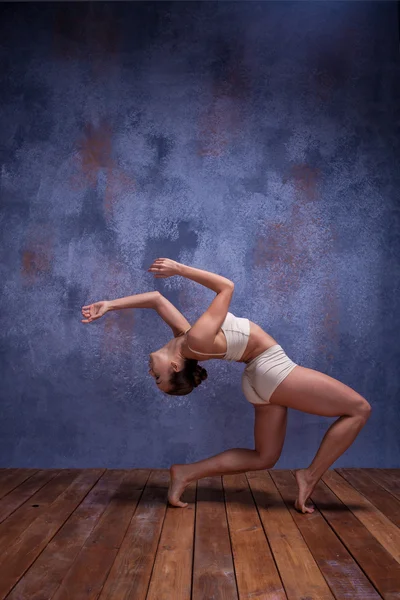 Junge schöne Tänzerin in beiger Badebekleidung tanzt auf fliederfarbenem Hintergrund — Stockfoto