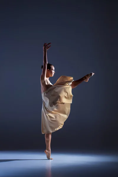 Joven hermosa bailarina en vestido beige bailando sobre fondo gris — Foto de Stock