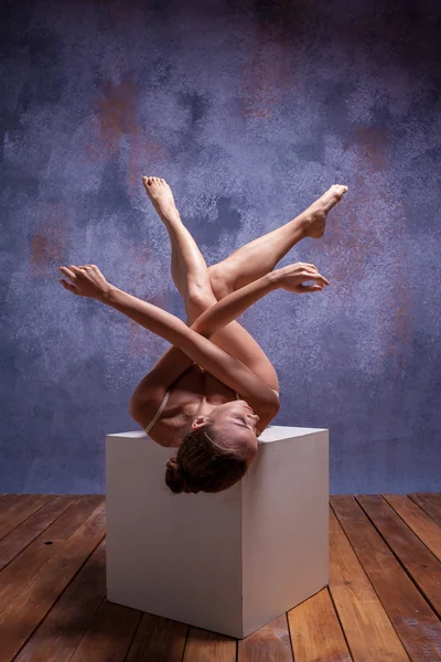 Young beautiful dancer in beige swimwear posing on white cube — Zdjęcie stockowe