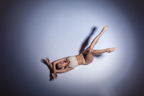 Giovane bella ballerina in costume da bagno beige che balla su sfondo lilla — Foto Stock