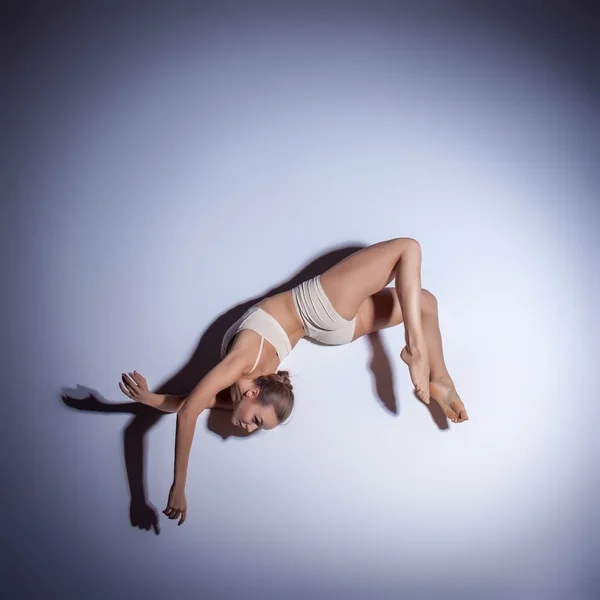 Jonge mooie danseres in beige badmode dansen op Lila achtergrond — Stockfoto