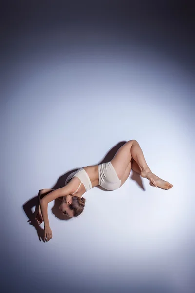 Joven hermosa bailarina en traje de baño beige bailando sobre fondo lila — Foto de Stock