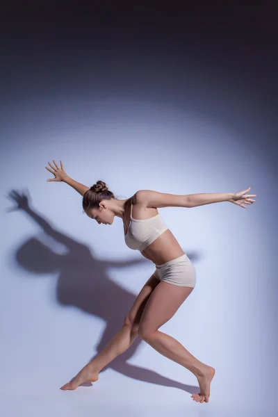 Jonge mooie danseres in beige badmode dansen op Lila achtergrond — Stockfoto