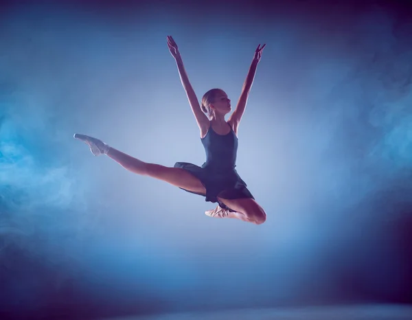 The silhouette of young ballet dancer jumping on a blue background. — Stock Photo, Image