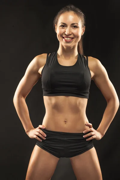 Musculosa joven atleta mirando en cámara en negro —  Fotos de Stock