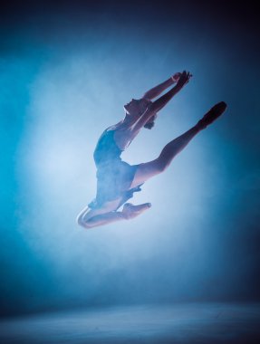 Genç balerin silueti mavi bir taşrada zıplıyor.