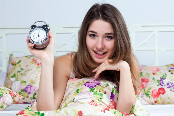 A jovem na cama com serviço de relógio — Fotografia de Stock