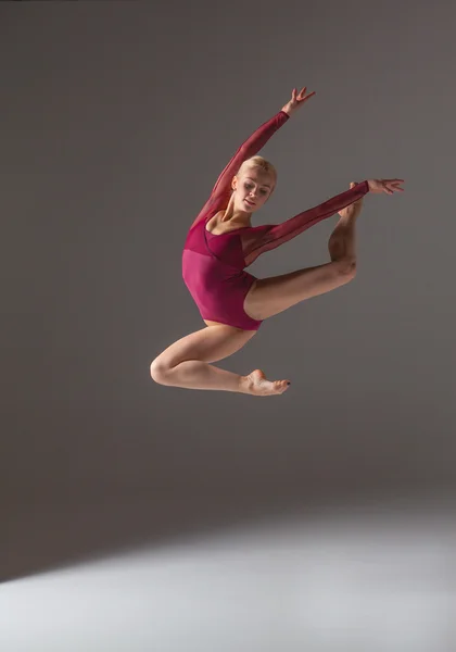 Young beautiful modern style dancer jumping on a studio background — Stock Photo, Image