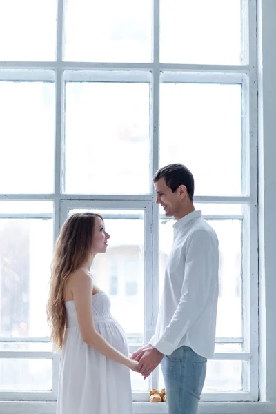 Alegre jovem casal vestido de branco sentado no sofá — Fotografia de Stock