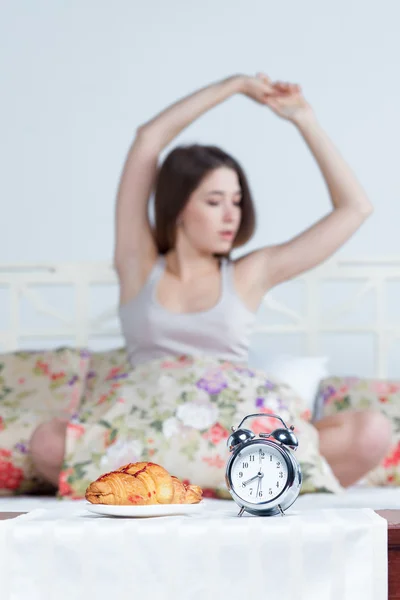 La joven en la cama con servicio de reloj — Foto de Stock
