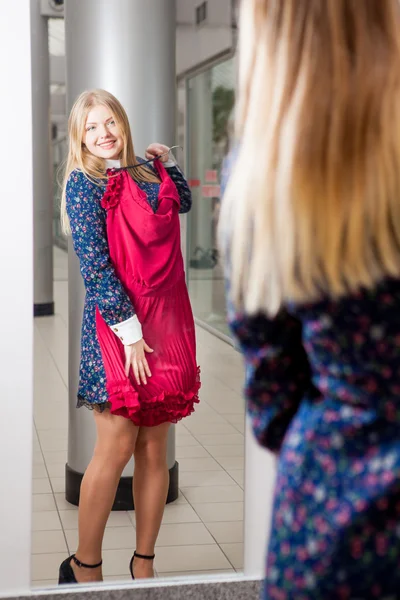 Mulher tentando vermelho vestido de compras para roupas . — Fotografia de Stock