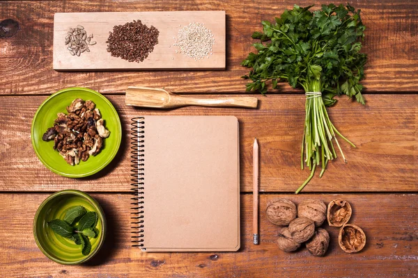 Σημειωματάριο για τις συνταγές, καρύδια, μαϊντανός και σπόρων προς σπορά σε ξύλινο τραπέζι. — Φωτογραφία Αρχείου