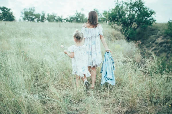 A jovem mãe e filha no fundo de grama verde — Fotografia de Stock