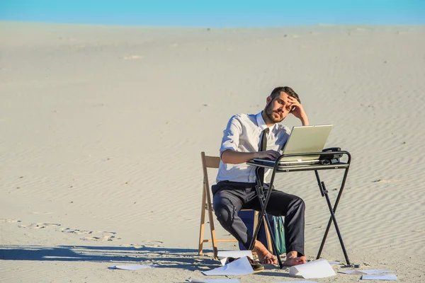 Hombre de negocios con ordenador portátil en un desierto — Foto de Stock