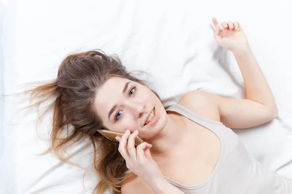 Το νεαρό κορίτσι στο κρεβάτι με τηλέφωνο — Φωτογραφία Αρχείου