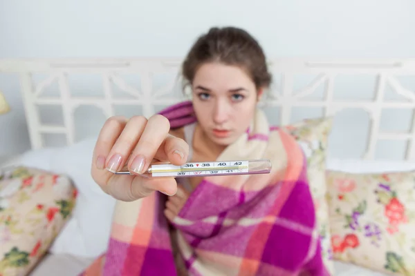 Jeune femme malade en couverture avec thermomètre — Photo
