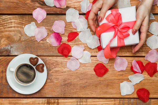 Regalo di San Valentino e mani femminili su sfondo di legno — Foto Stock