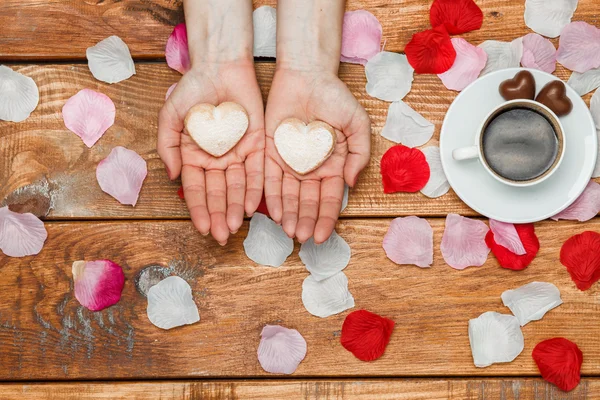 Conceito do Dia dos Namorados. Mãos femininas com corações em fundo de madeira — Fotografia de Stock