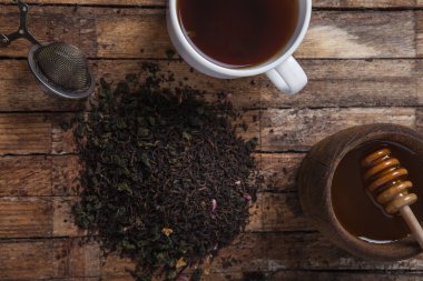 The cup of tea and honey on a wooden table
