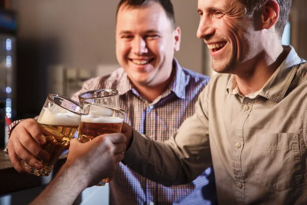 Amigos felizes bebendo cerveja no balcão no pub — Fotografia de Stock