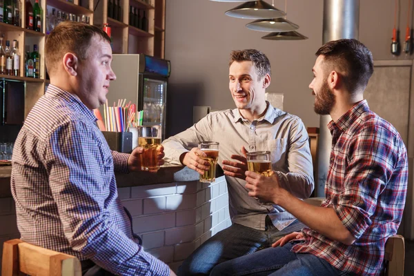 Amici felici che bevono birra al bancone nel pub — Foto Stock