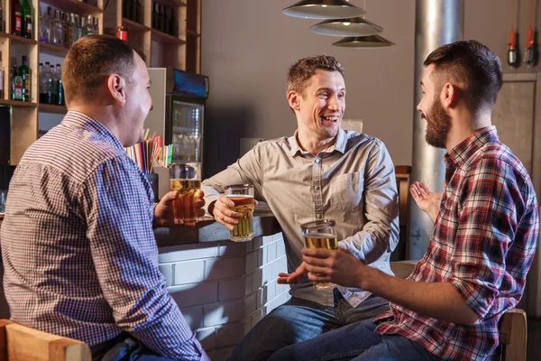 Amigos felizes bebendo cerveja no balcão no pub — Fotografia de Stock