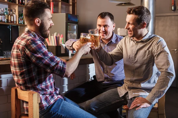 Amigos felizes bebendo cerveja no balcão no pub — Fotografia de Stock