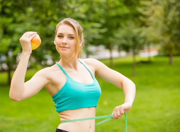 Deportiva joven con manzana y cinta métrica — Foto de Stock