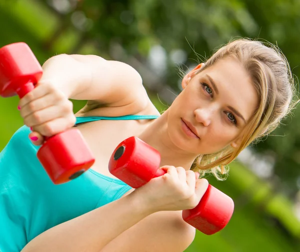 Sport meisje oefening met halters in het park — Stockfoto